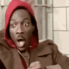 A Man Wearing A Red Hoodie Is Making A Surprised Face While Holding A Cell Phone . GIF