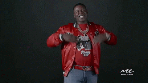 a man wearing a red jacket and a heavy camp shirt is standing in front of a black background .