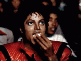 A Man Wearing A Red Jacket Is Covering His Mouth With His Hand GIF