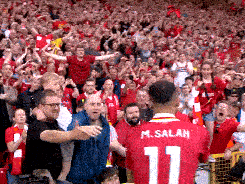 A Man Wearing A Red Jersey With The Number 11 On It Stands In Front Of A Crowd GIF