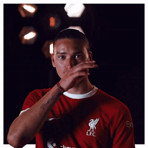 A Man Wearing A Red Lfc Shirt Is Covering His Face With His Hand GIF