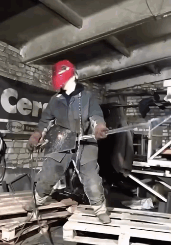 A Man Wearing A Red Mask Is Welding In Front Of A Sign That Says Cern GIF