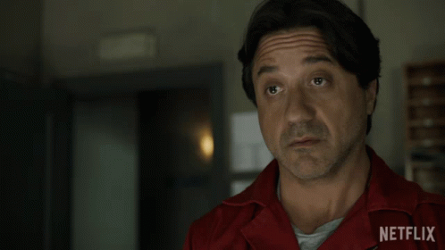 A Man Wearing A Red Netflix Shirt Looks At The Camera GIF