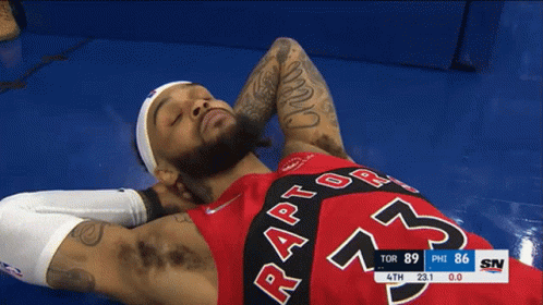 A Man Wearing A Red Raptors Jersey Laying On The Floor GIF