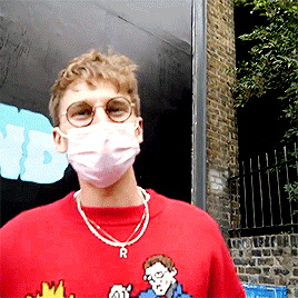 A Man Wearing A Red Shirt And A Mask With The Letter R On His Neck GIF