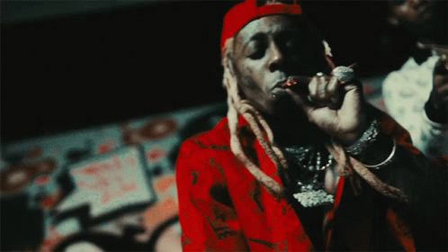 A Man Wearing A Red Shirt And A Red Hat Is Smoking A Cigarette GIF
