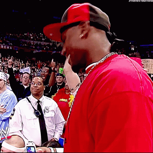 A Man Wearing A Red Shirt And A Red Hat Is Standing In Front Of A Crowd .. GIF