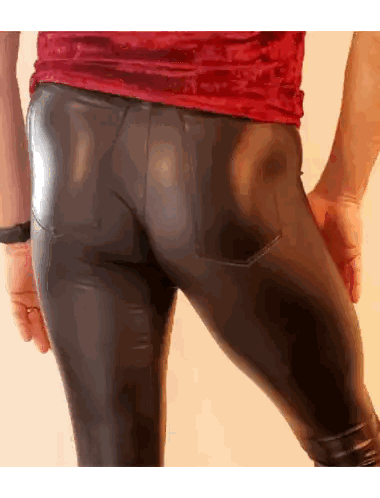 a man wearing a red shirt and black pants has his hands in his pockets