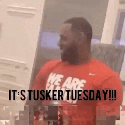 a man wearing a red shirt that says it 's tusker tuesday .