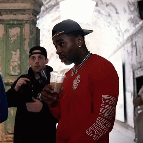 A Man Wearing A Red Shirt That Says Kevin Gates On The Sleeve GIF