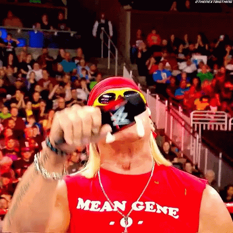 A Man Wearing A Red Shirt That Says Mean Gene Holds A Bottle In His Hand GIF