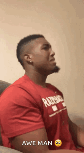 a man wearing a red shirt that says razorback is sitting on a couch