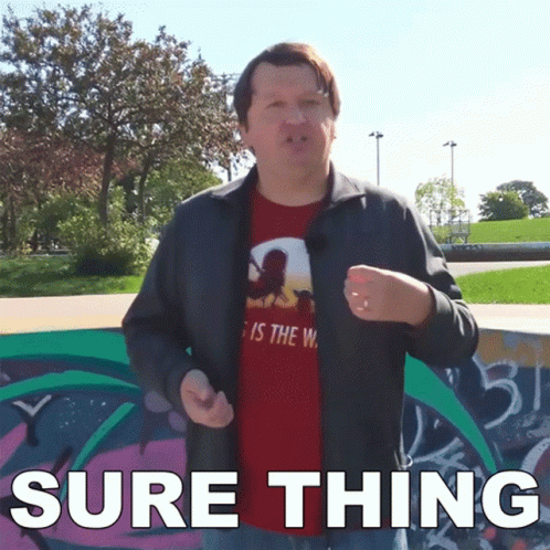 A Man Wearing A Red Shirt That Says " Sure Thing " Stands In Front Of A Graffiti Wall GIF