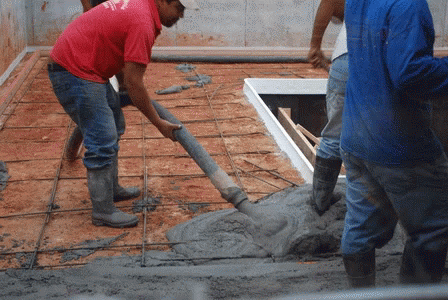 A Man Wearing A Red Shirt That Says ' Texas ' On It Pours Concrete GIF