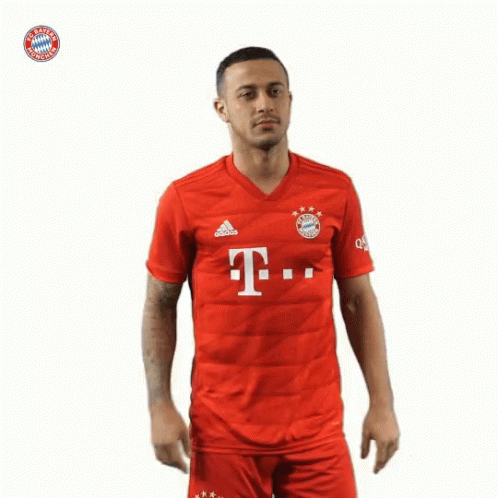 A Man Wearing A Red Shirt With The Bayern Munich Logo On The Front GIF