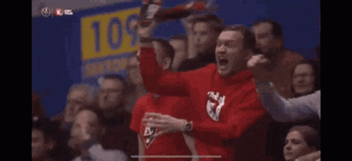 A Man Wearing A Red Shirt With The Letter K On It Is Screaming In A Crowd GIF