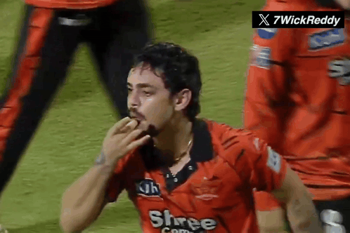 A Man Wearing A Red Shree Com Jersey Eating Something GIF