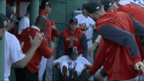 A Man Wearing A Red Sox Sweatshirt Is Surrounded By Other Baseball Players GIF