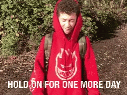 A Man Wearing A Red Spitfire Hoodie Is Standing In A Forest GIF