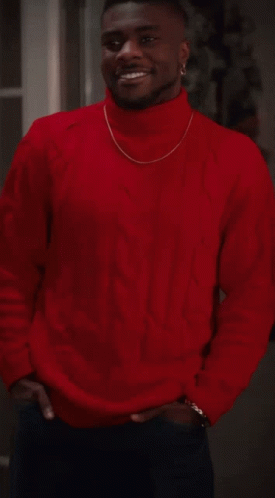 A Man Wearing A Red Sweater And A Gold Chain Around His Neck Smiles GIF