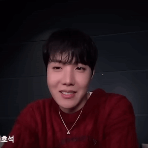 A Man Wearing A Red Sweater And A Necklace With The Letter A On It GIF