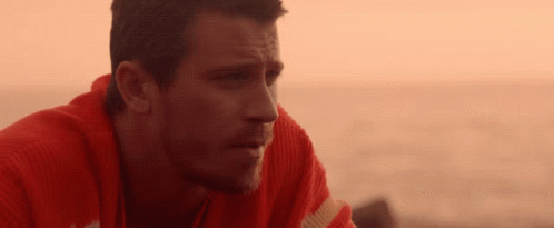 A Man Wearing A Red Sweater Looks At The Ocean GIF