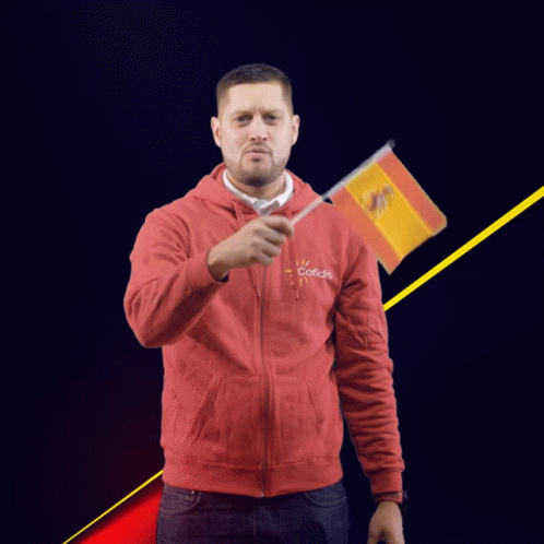 A Man Wearing A Red Sweatshirt That Says Cofidis Holds A Small Spanish Flag GIF