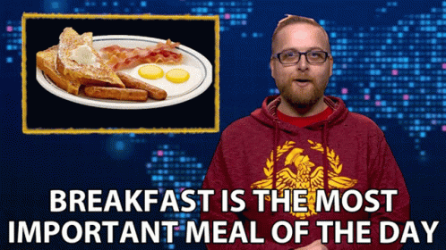 A Man Wearing A Red Sweatshirt With An Eagle On It Stands In Front Of A Plate Of Breakfast GIF
