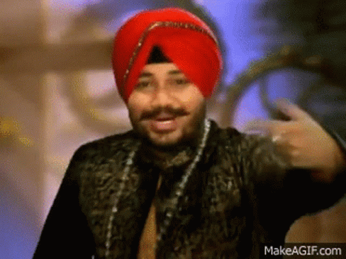A Man Wearing A Red Turban And A Black Jacket Is Making A Funny Face . GIF