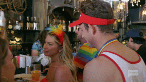 A Man Wearing A Red Visor Is Talking To A Woman In A Red Dress GIF