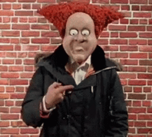 A Man Wearing A Red Wig And A Mask Is Pointing At Something . GIF