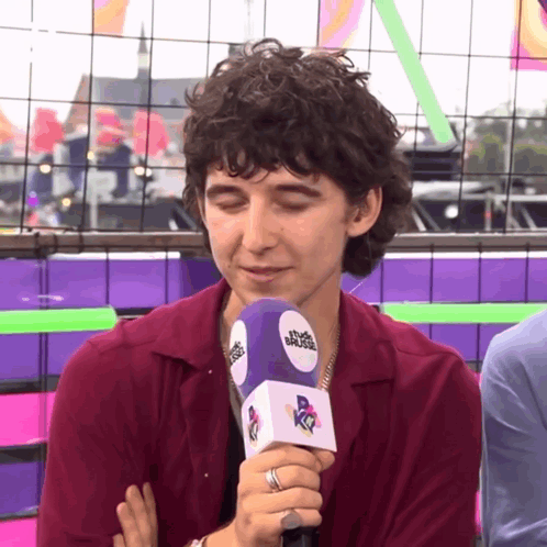 A Man Wearing A Ring Is Holding A Microphone With The Word Muse On It GIF