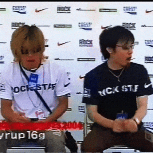 Man In Rock Staff Shirt Next To Man In Black GIF