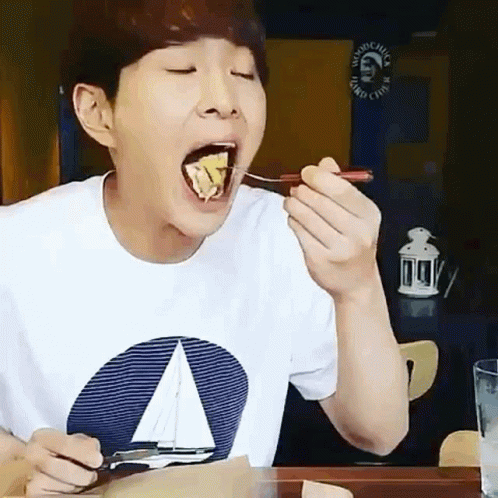 A Man Wearing A Sailboat Shirt Is Eating Food With A Spoon GIF
