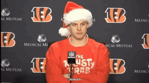 A Man Wearing A Santa Hat And A Red Sweater That Says " The Lusty Krab " GIF