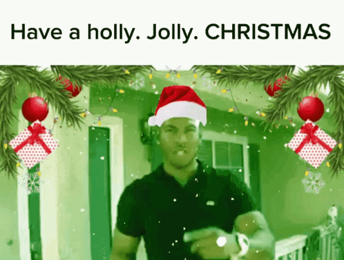 A Man Wearing A Santa Hat Is Surrounded By Christmas Decorations GIF
