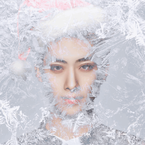 A Man Wearing A Santa Hat Is Surrounded By Snowflakes GIF