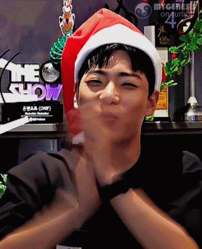 A Man Wearing A Santa Hat With The Word Show Behind Him GIF