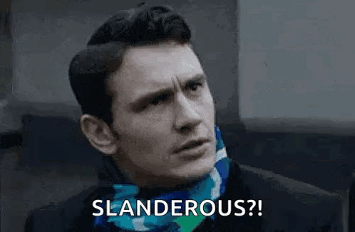 A Man Wearing A Scarf Around His Neck Is Making A Funny Face And Says Slanderous . GIF