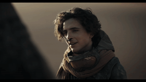 A Man Wearing A Scarf Around His Neck Looks To The Side GIF