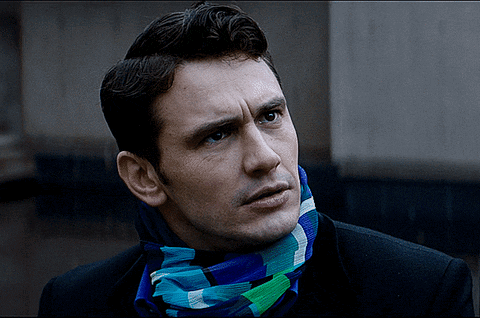 a man wearing a scarf around his neck looks to the side