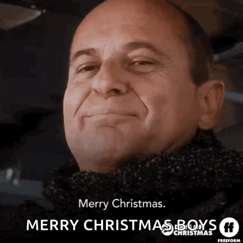 A Man Wearing A Scarf Is Smiling And Wishing Merry Christmas GIF