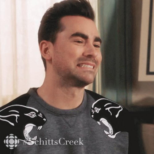 A Man Wearing A Schitts Creek Shirt Smiles GIF