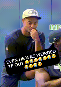 a man wearing a seahawks hat is holding another man 's hand