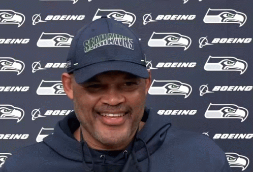 a man wearing a seahawks hat stands in front of a boeing logo