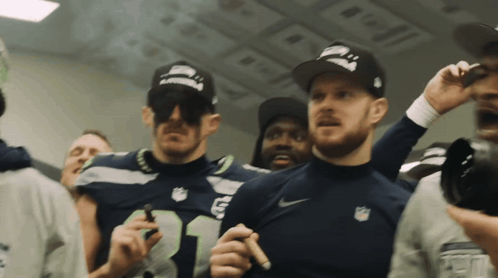 a man wearing a seahawks jersey stands in a crowd of people