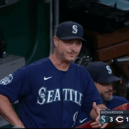 A Man Wearing A Seattle Jersey Is Laughing In The Dugout GIF