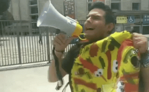 A Man Wearing A Sesame Street Shirt Holds A Megaphone GIF