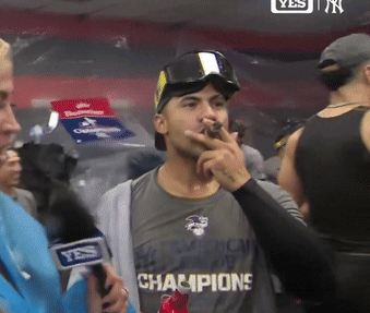A Man Wearing A Shirt That Says " Champions " Smoking A Cigar GIF
