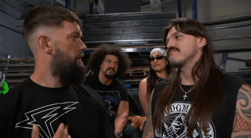 A Man Wearing A Shirt That Says Dgm Stands In Front Of Two Other Men GIF
